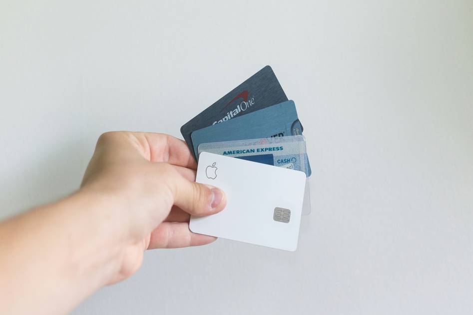 Car rental lot with traveler holding credit card near vehicle, symbolizing car rental insurance coverage